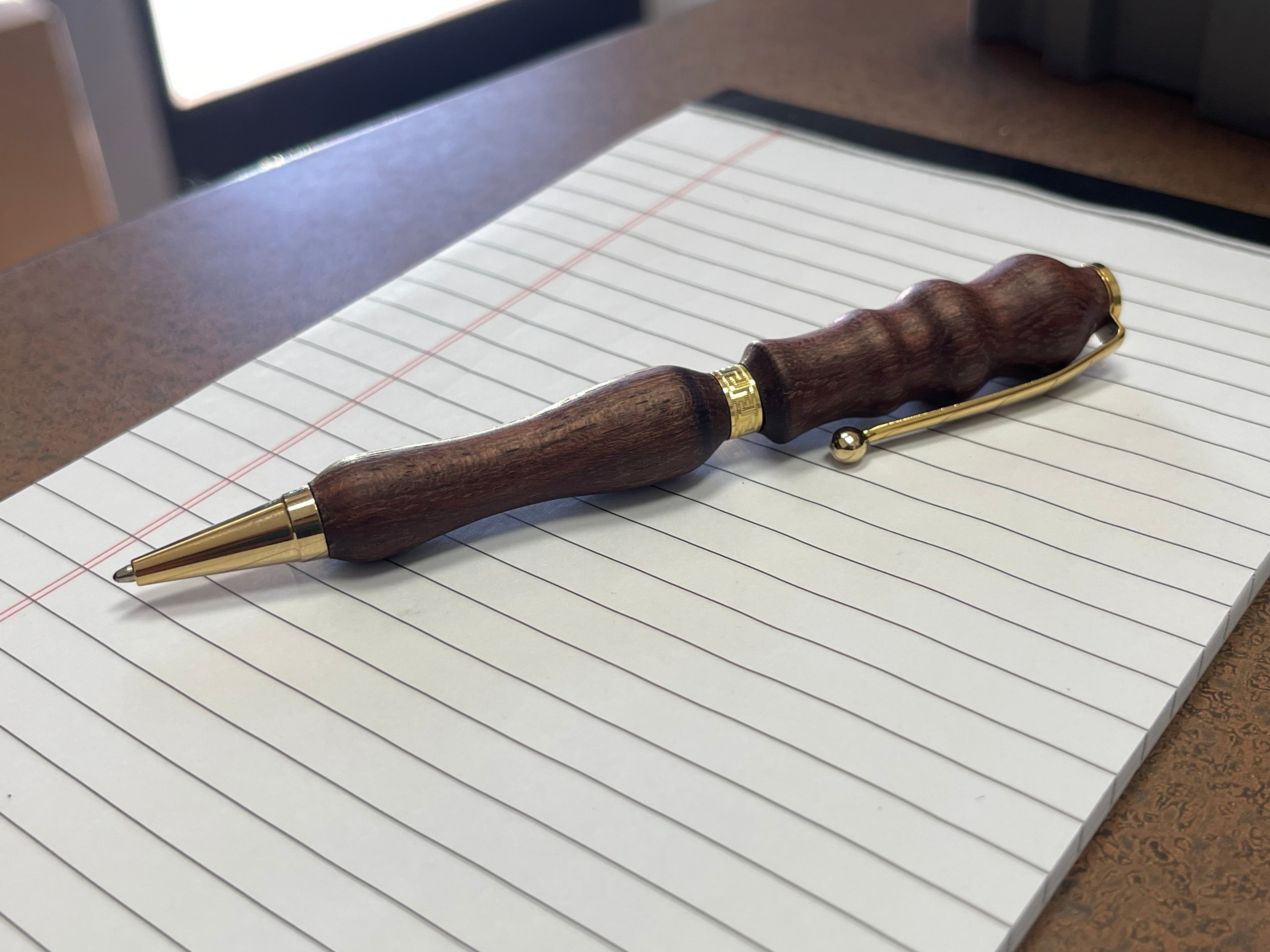 Wooden pen with gold accents on a piece of lined paper