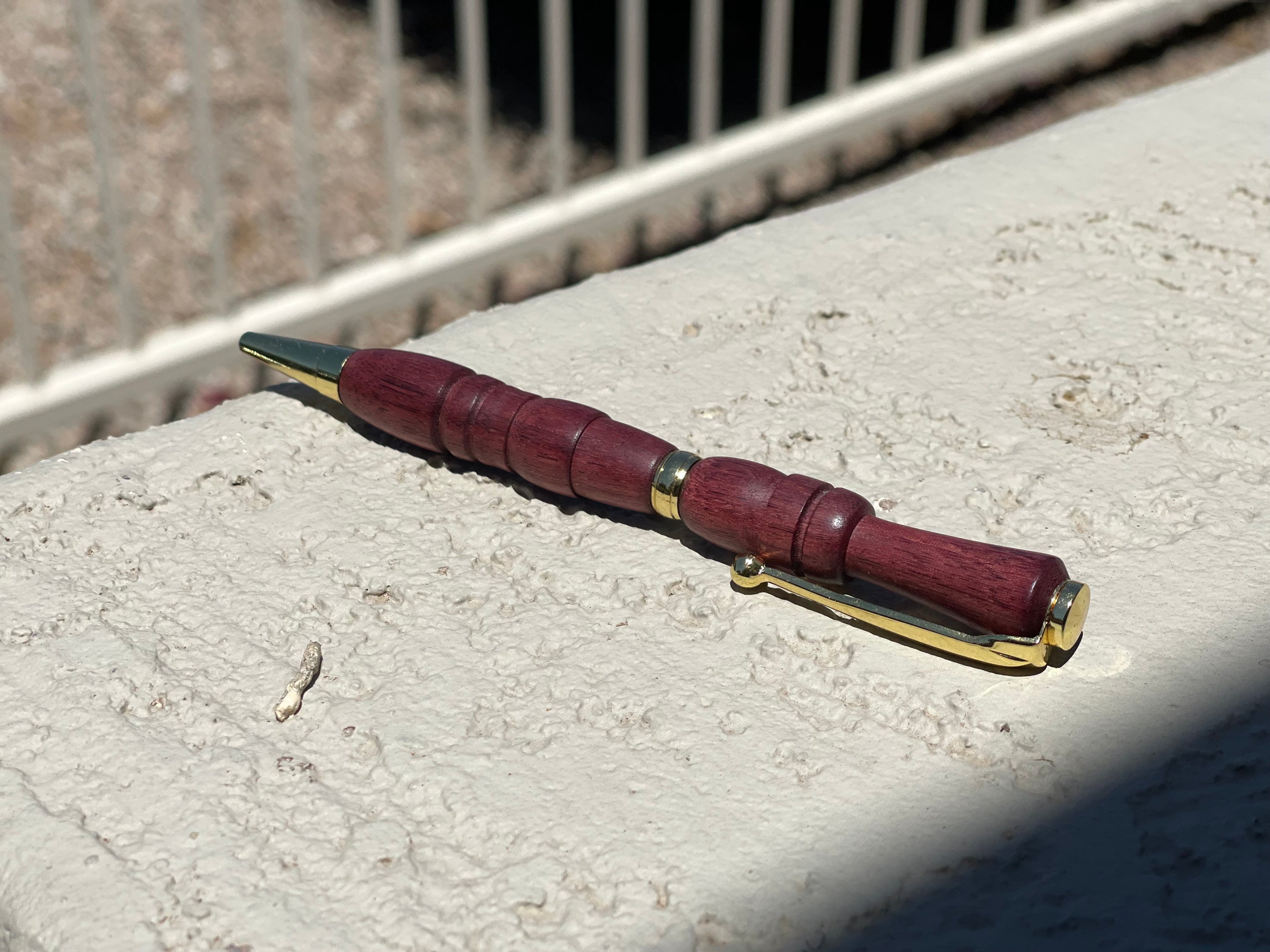 Wooden pen with gold accents on a concrete surface