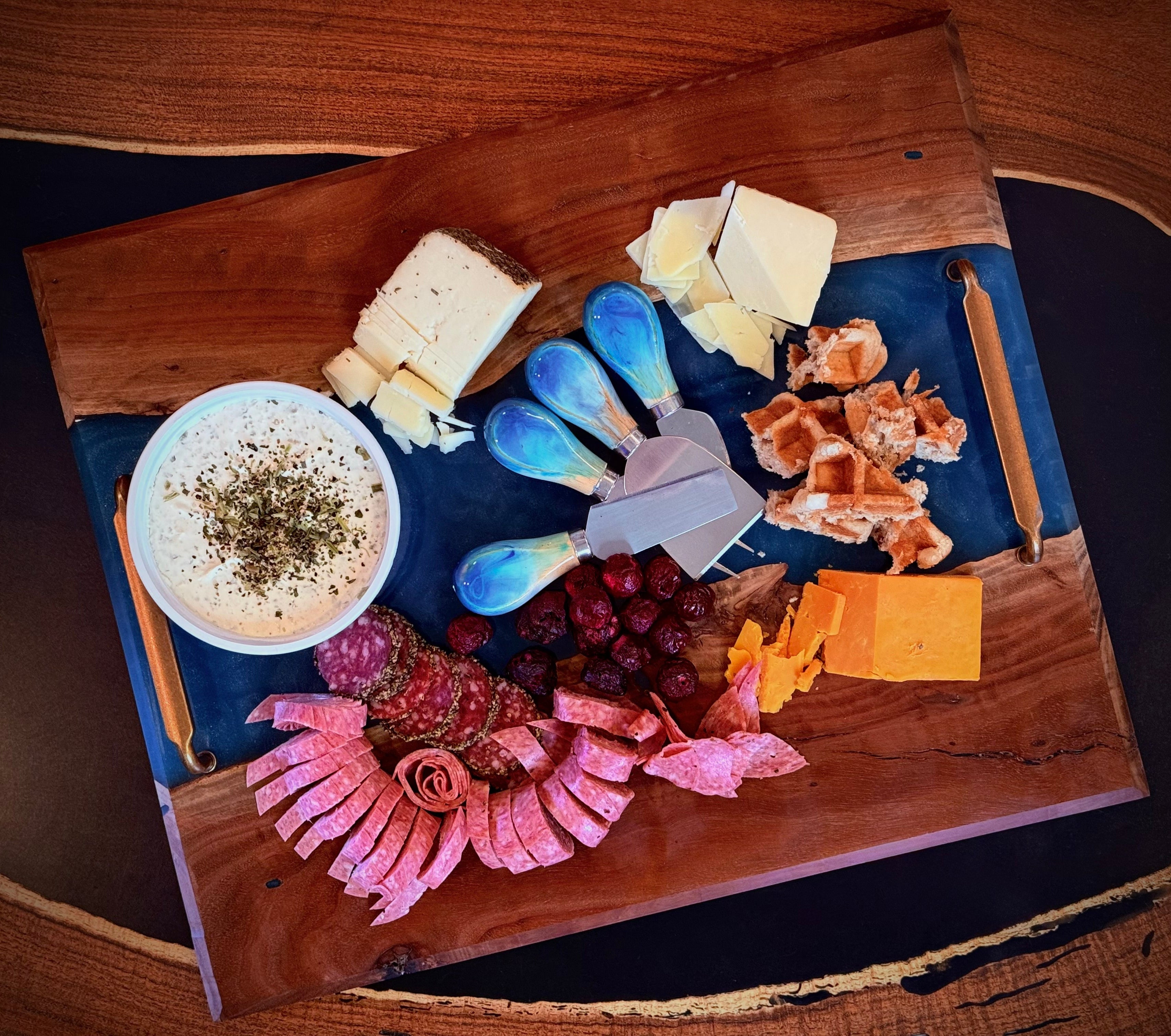 Wooden charcuterie board with various meats, cheeses, and a bowl of dip.